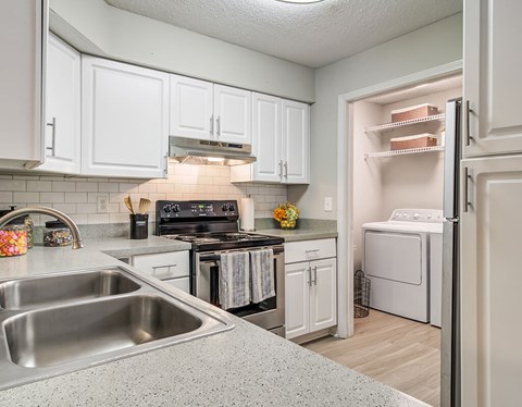 A kitchen with white cabinets and a stainless steel sink.
